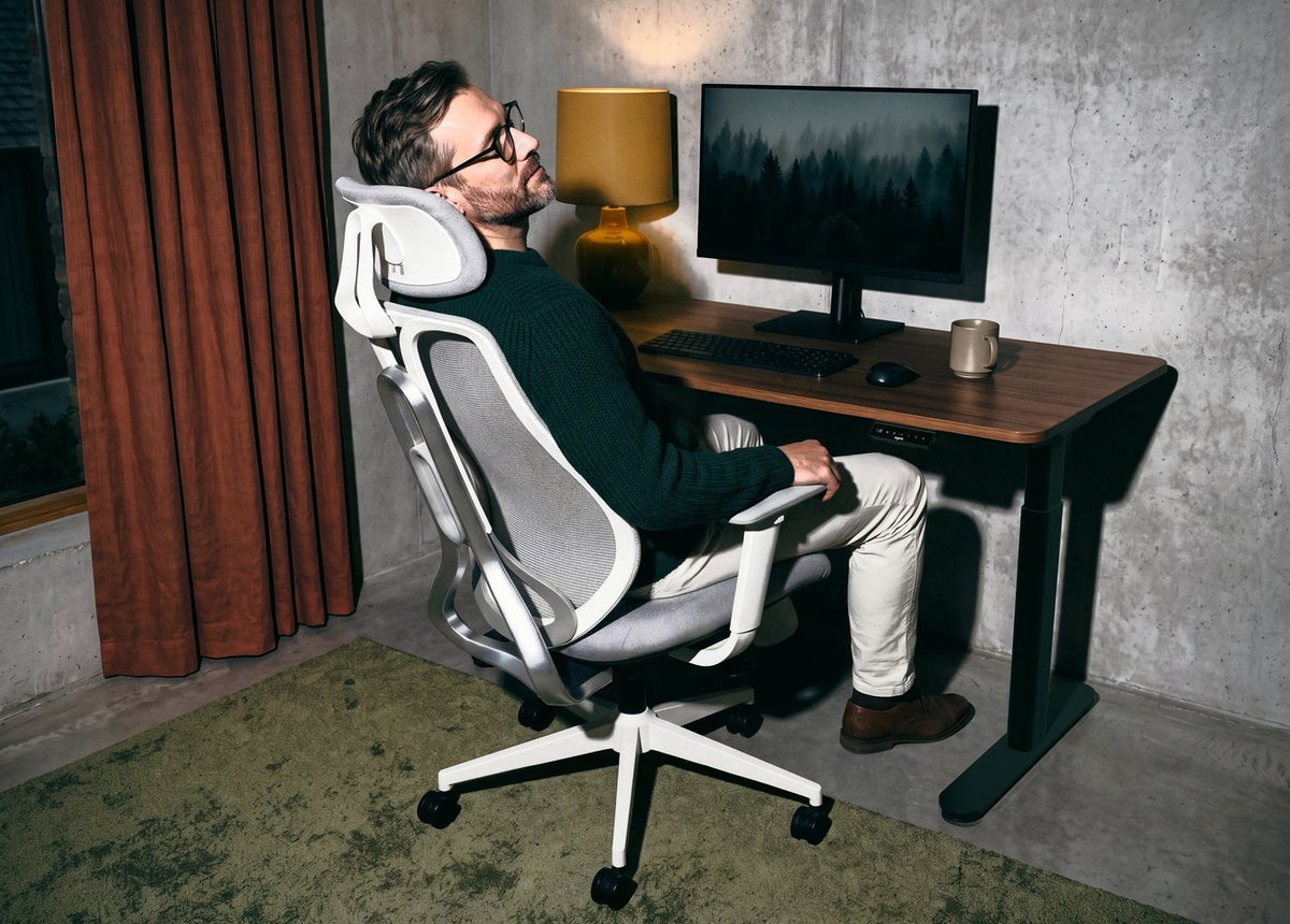 Muž zakloněný na ergonomické židli OmniSit Pro u pracovního stolu